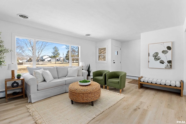 living room with a baseboard radiator, visible vents, and light wood-style flooring