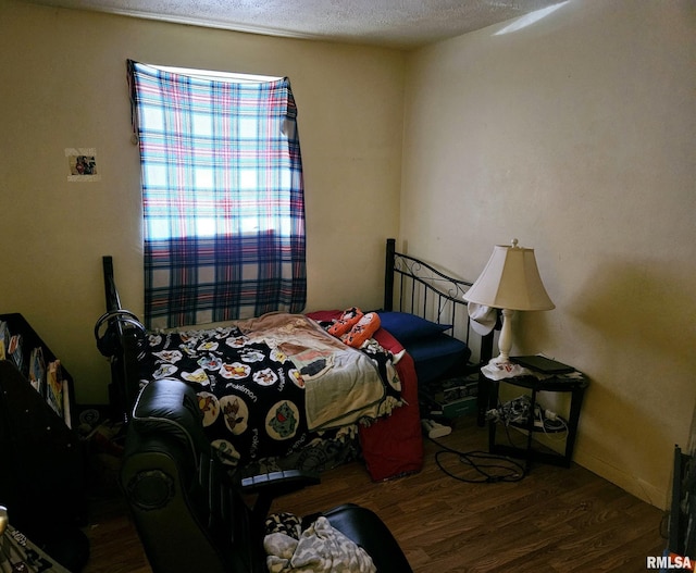 bedroom with a textured ceiling, baseboards, and wood finished floors