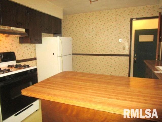 kitchen featuring wallpapered walls, wood counters, freestanding refrigerator, gas range oven, and under cabinet range hood