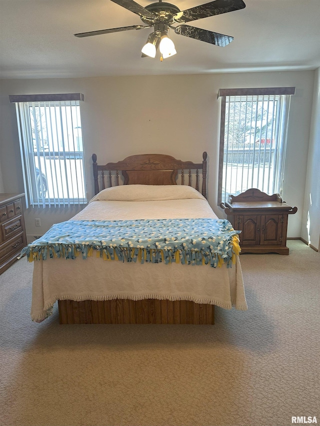 bedroom featuring light carpet, multiple windows, and a ceiling fan