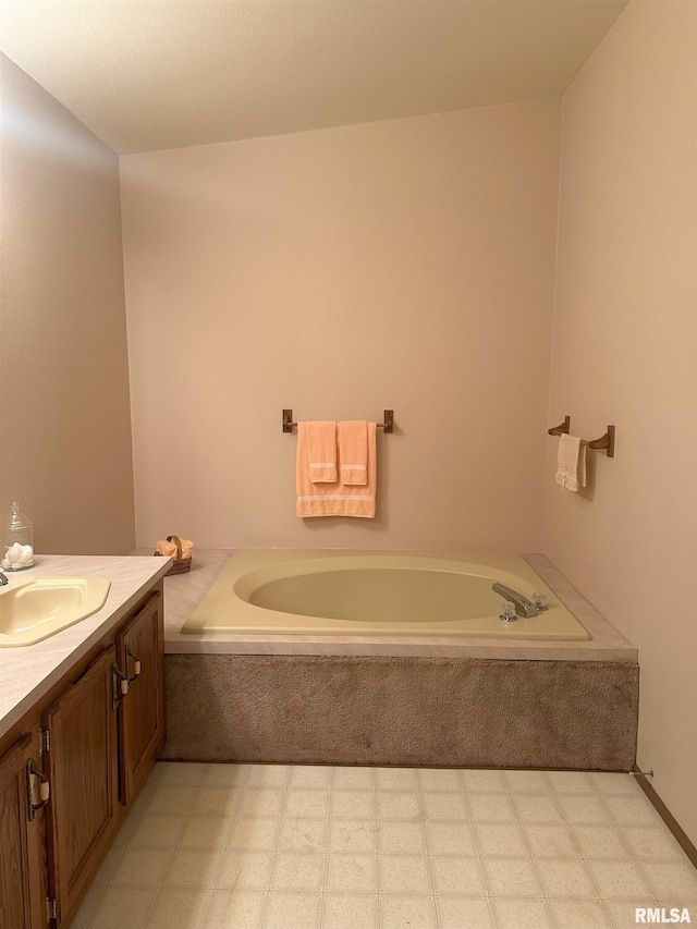 bathroom with a garden tub, vanity, and tile patterned floors