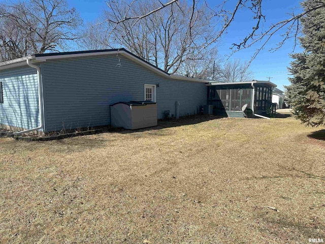 view of side of property with cooling unit, a sunroom, and a lawn