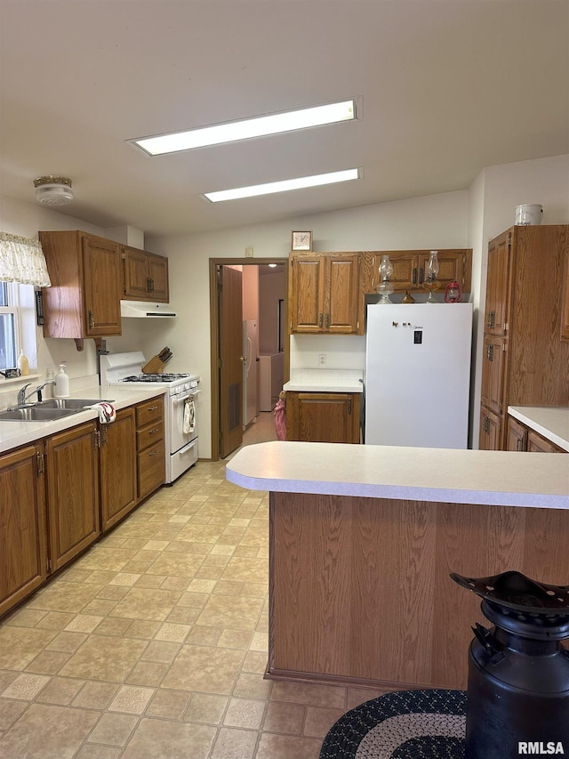 kitchen featuring light countertops, white appliances, a sink, and brown cabinets