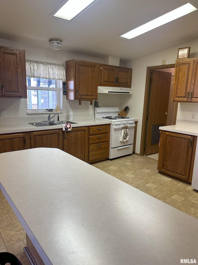 kitchen featuring light countertops, white range with gas cooktop, a sink, and extractor fan