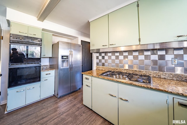 kitchen with green cabinetry, backsplash, appliances with stainless steel finishes, and dark wood-style floors