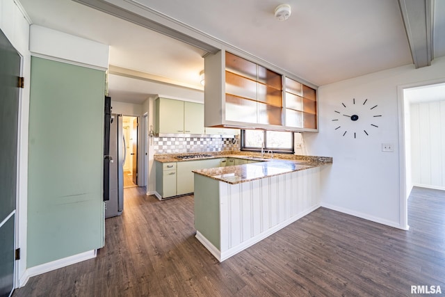 kitchen with light stone counters, dark wood-style floors, a peninsula, appliances with stainless steel finishes, and decorative backsplash