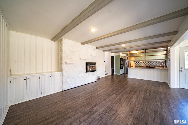 unfurnished living room with beam ceiling, a stone fireplace, stairs, and dark wood-type flooring