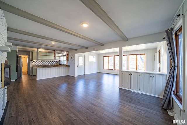 unfurnished living room with beam ceiling, dark wood finished floors, and a fireplace