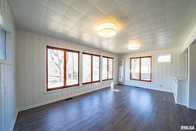 empty room with dark wood-type flooring, baseboards, and visible vents