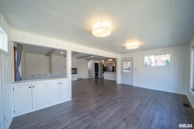 spare room featuring dark wood-type flooring, stairway, and visible vents