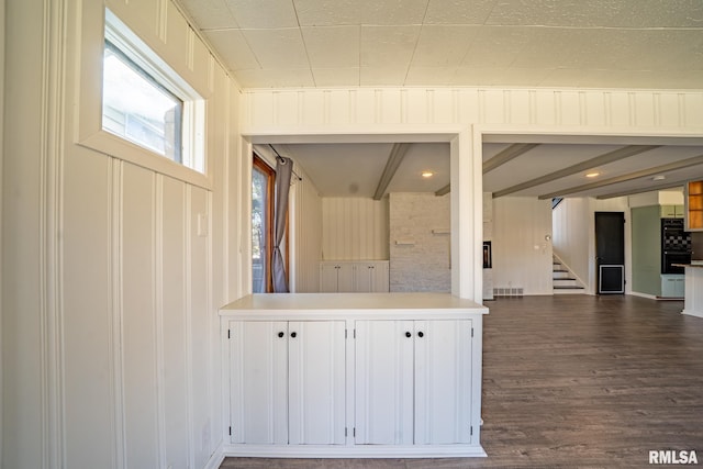 kitchen with visible vents, dark wood-type flooring, beamed ceiling, light countertops, and white cabinetry