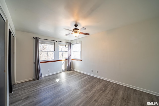 empty room with dark wood-style floors, baseboards, and ceiling fan