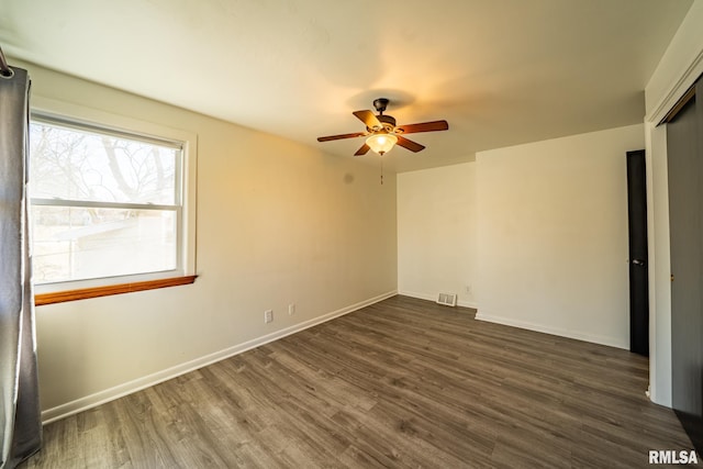 empty room with visible vents, baseboards, ceiling fan, and dark wood-style flooring