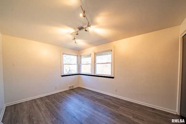 unfurnished room with dark wood-style floors, visible vents, and baseboards