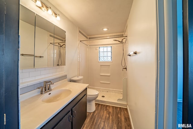 bathroom with toilet, wood finished floors, a shower stall, decorative backsplash, and vanity