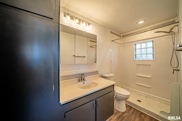 full bathroom with toilet, a stall shower, backsplash, wood finished floors, and vanity