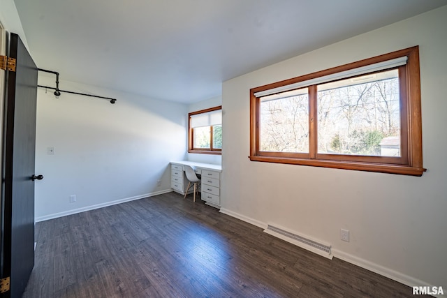 unfurnished bedroom with dark wood-style floors, visible vents, built in desk, and baseboards