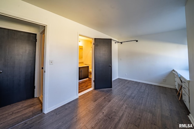 unfurnished bedroom featuring lofted ceiling, baseboards, and dark wood-style flooring