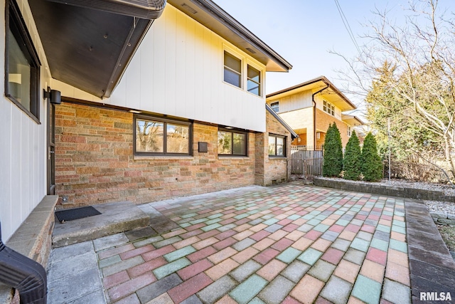 back of property featuring a patio, fence, and stone siding