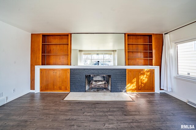 unfurnished living room with visible vents, a fireplace with flush hearth, built in features, wood finished floors, and baseboards