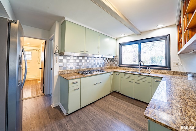 kitchen featuring a sink, appliances with stainless steel finishes, green cabinetry, decorative backsplash, and dark wood-style flooring