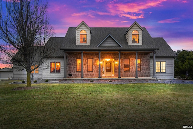 view of front of house featuring a shingled roof, a front lawn, a porch, and brick siding