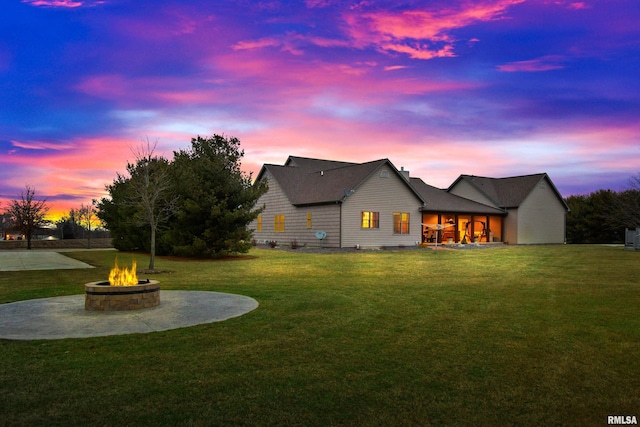 back of house at dusk with an outdoor fire pit, a lawn, and a patio