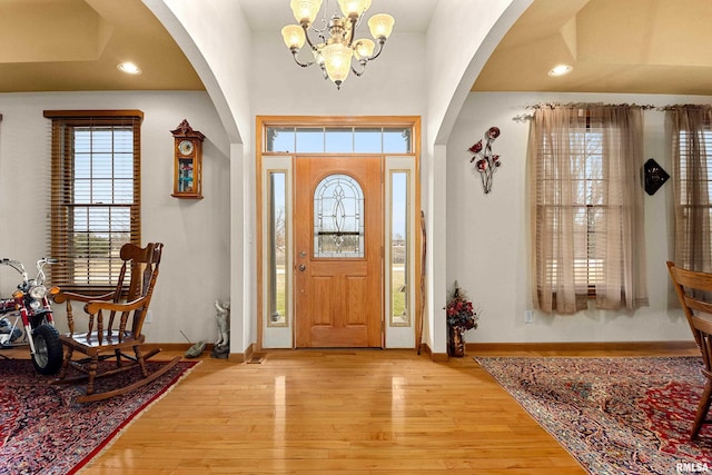 foyer entrance with baseboards, arched walkways, light wood-style floors, a chandelier, and recessed lighting