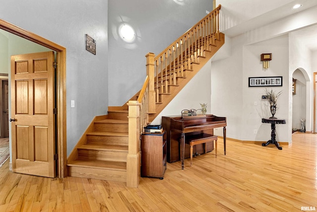 staircase with arched walkways, hardwood / wood-style floors, recessed lighting, and baseboards