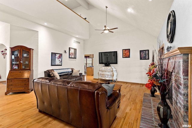 living room featuring beam ceiling, visible vents, light wood-style floors, high vaulted ceiling, and baseboards