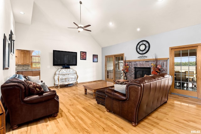 living area featuring light wood finished floors, a ceiling fan, a brick fireplace, high vaulted ceiling, and recessed lighting