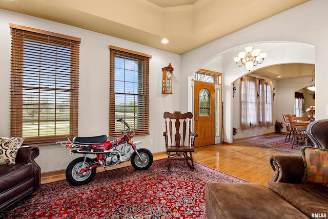 foyer entrance with baseboards, arched walkways, wood finished floors, a notable chandelier, and recessed lighting