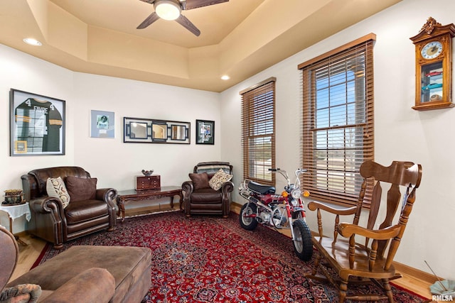 living area featuring ceiling fan, baseboards, a tray ceiling, and recessed lighting