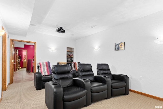 cinema room with light carpet, visible vents, and baseboards