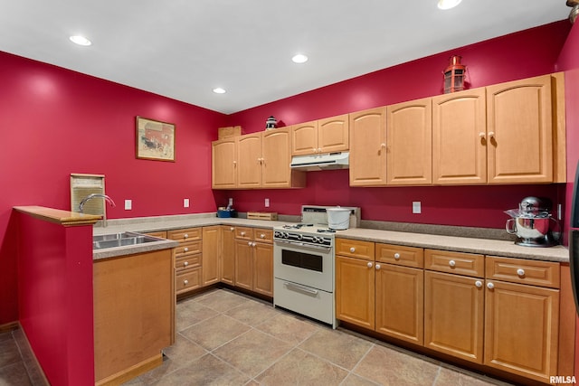 kitchen with a peninsula, gas range gas stove, under cabinet range hood, a sink, and recessed lighting