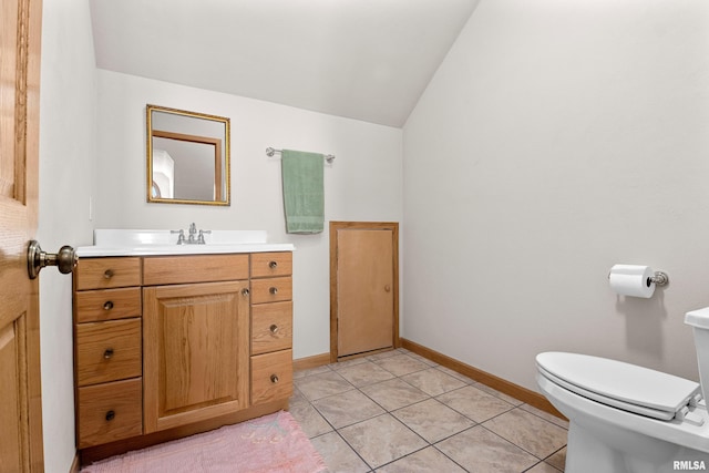 half bathroom featuring toilet, vanity, baseboards, vaulted ceiling, and tile patterned floors