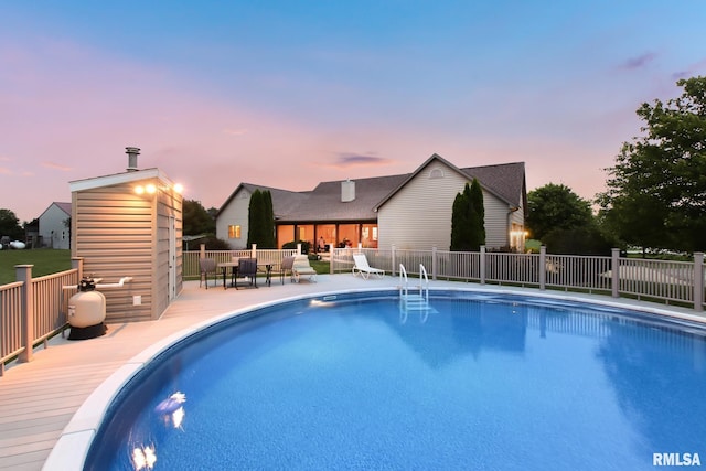 pool at dusk featuring a fenced in pool and fence