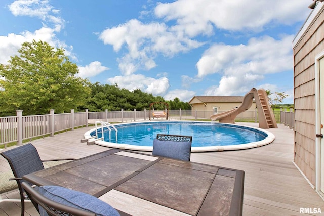 view of swimming pool with a fenced in pool, a water slide, fence, and a deck