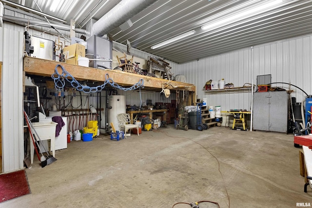 garage featuring water heater, a workshop area, metal wall, and a sink