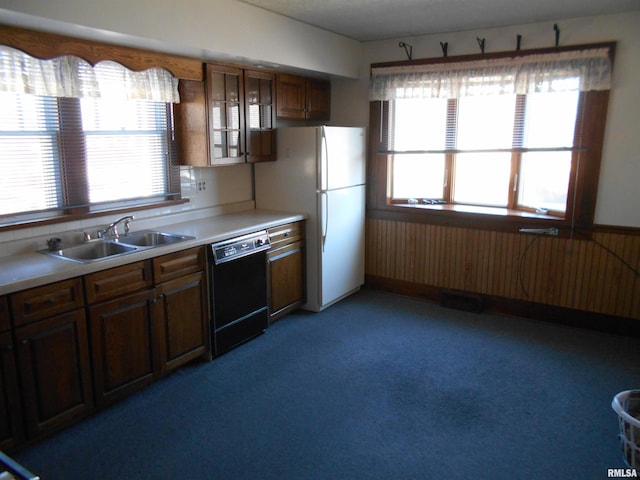 kitchen featuring a sink, light countertops, wainscoting, freestanding refrigerator, and dishwasher