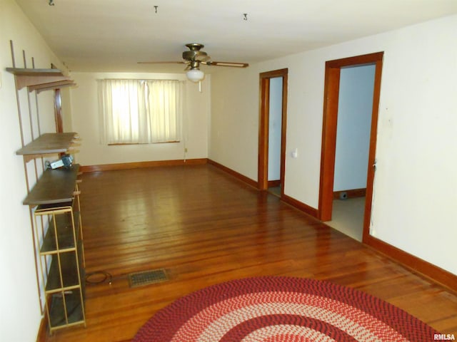 interior space featuring ceiling fan, wood finished floors, visible vents, and baseboards