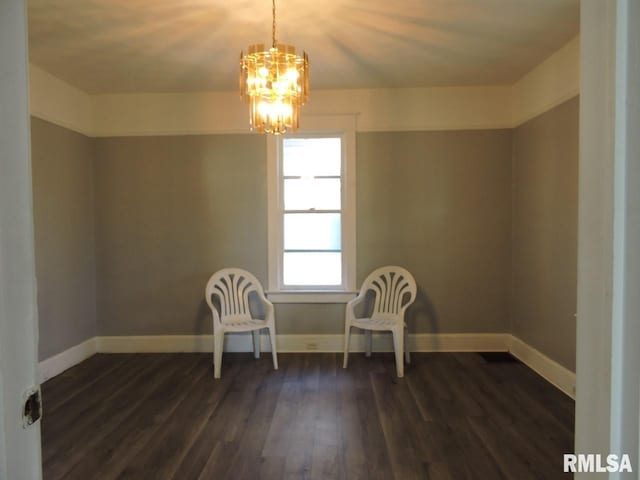 unfurnished room with dark wood-type flooring, a notable chandelier, and baseboards