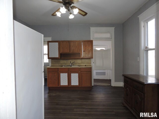 kitchen with dark wood-style flooring, a sink, a ceiling fan, decorative backsplash, and brown cabinets