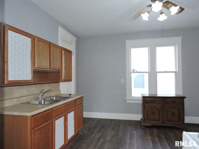 kitchen featuring tasteful backsplash, baseboards, dark wood finished floors, light countertops, and a sink