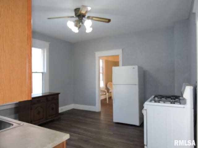 kitchen with dark wood-style flooring, light countertops, a ceiling fan, white appliances, and baseboards