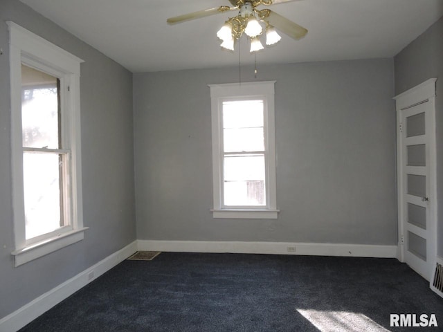 unfurnished room featuring ceiling fan, visible vents, baseboards, and dark carpet