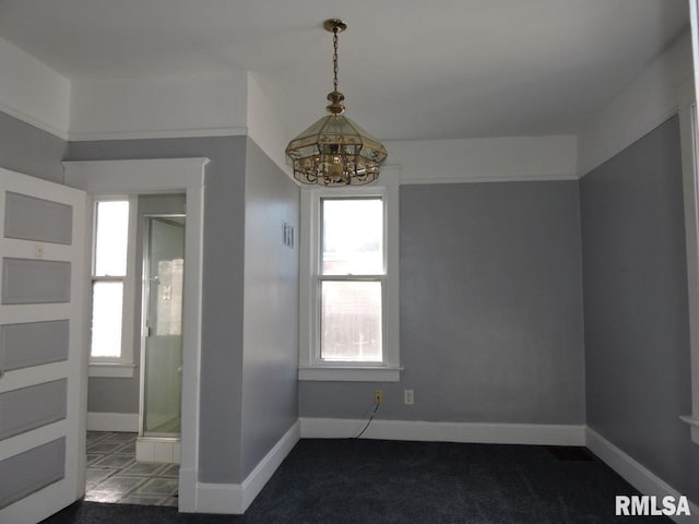 empty room featuring carpet floors, baseboards, and a notable chandelier