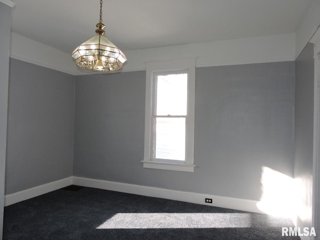 empty room with a chandelier, dark colored carpet, and baseboards