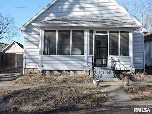 bungalow-style house featuring a shingled roof, a sunroom, and fence