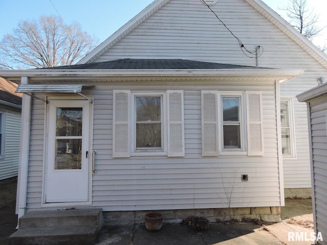 view of side of home featuring entry steps and a shingled roof